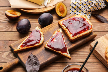 Slices of bread with delicious homemade plum jam on wooden background