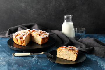 Board with tasty peach pie on dark background