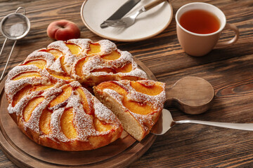 Board with tasty peach pie on wooden background