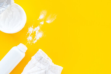 Set of children's cosmetics on a yellow background, top view, copy space, mockup. Baby hygiene, trendy minimalistic background. Flat lay composition diaper, powder, cream