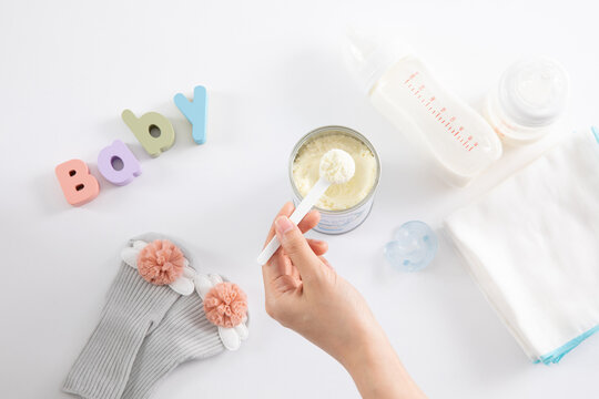 A High Angle Shot Of A Female Hand And Baby Care Items On White Surface