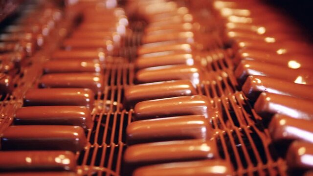 Sweets are being glazed with chocolate during manufacturing