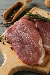 Board with raw steak meat, herbs and spices on wooden background