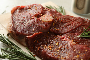 Baking paper with raw steak meat, herbs and spices, close up