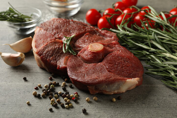 Fresh raw steak meat, herbs and spices on gray background