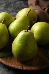Wooden tray with green pears on black smokey background
