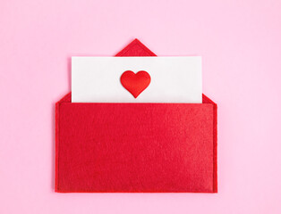 Red open envelope with a sheet of paper with a heart on a pink background with copyspace. Valentine's day holidays concept and love notes, christmas and new year  letters for Santa Claus