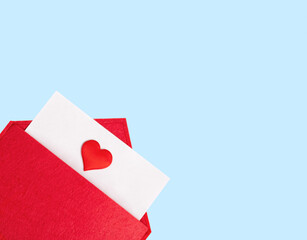 Red open envelope with a sheet of paper with a heart on a blue background with copyspace. Valentine's day holidays concept and love notes, christmas and new year  letters for Santa Claus