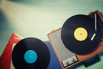 Old record player from the 70s with a vinyl records on green wooden table, top view and copy space.