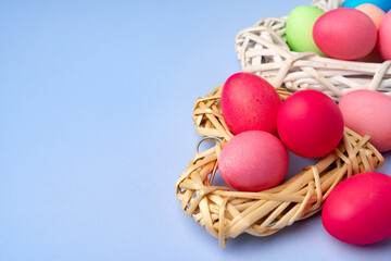 Fototapeta na wymiar Colorful Easter eggs in decorative nest on blue background