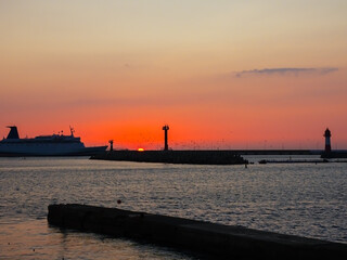 Fototapeta na wymiar The ship enters the sea bay against the backdrop of the setting sun