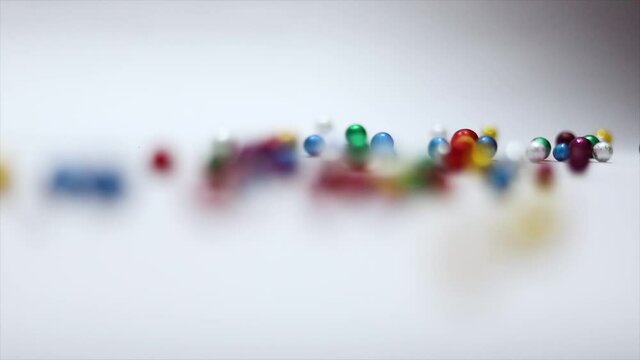 Multi-colored balls falling and scattering in different directions and rolling on a white background