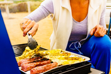 Hand grilling sausages and chicken meat on grill