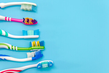 Multi-colored toothbrushes on a blue background. Flat composition with hand toothbrushes on colored background, close up with copy space.