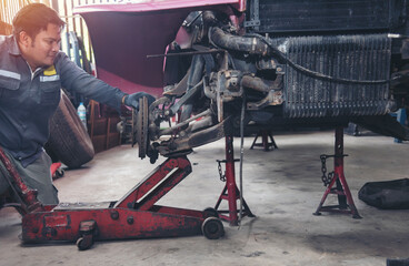 Fototapeta premium asia man in blue uniform car mechanic sitting check car engine motor machine at garage. owner sme business transport industrial people person concept