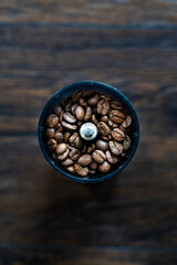 Coffee Beans in Coffee Mill or Grinder on Wooden Table.