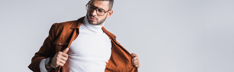 Fashionable man holding terracotta jacket isolated on grey, banner
