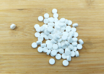 Fototapeta na wymiar white pills on wooden background