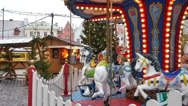 Carousel at winter market. Close up of a moving Carousel, roundabout or merry-go-round surrounded with retro vintage wooden seat and horses. Atmosphere of amusement park.