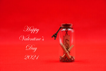 Valentine 2021 , Love word inside glass bottle on red background with Happy valentine's day 2021 word on copy space . Love celebration postcard concept 