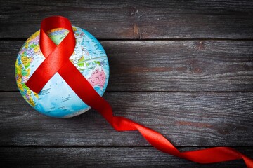 World Cancer Day. Cancer awareness. Red ribbon and globe on a wooden background. International...
