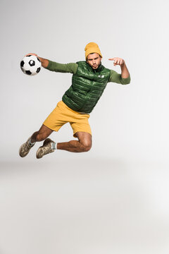 Sportsman Pointing With Finger At Football Mid Air On Grey Background