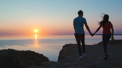 Fototapeta premium The man and woman walking holding hands on the beautiful seascape background