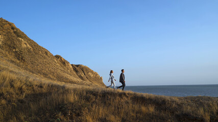 The two tourists walking in the mountains near the sea