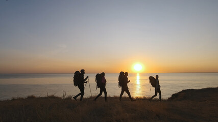 The four travelers with backpacks walking on the seascape background