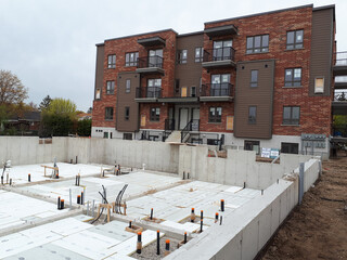 A modern residential building with a new building construction site in front