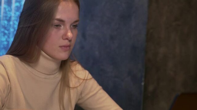 Young woman works behind notebooks while sitting in a cafe.