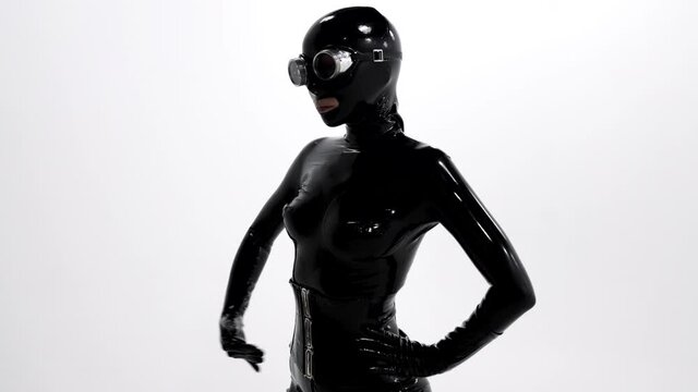 voluptuous woman in black latex costume is dancing seductively at white background, sex shop clothes