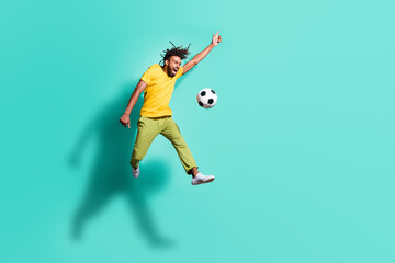 Fototapeta na wymiar Full size photoo of young happy positive crazy african man jumping playing football isolated on turquoise color background
