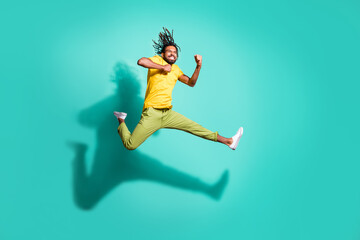 Naklejka na ściany i meble Full size photo of young happy excited crazy smiling african man jumping wear yellow t-shirt isolated on teal color background