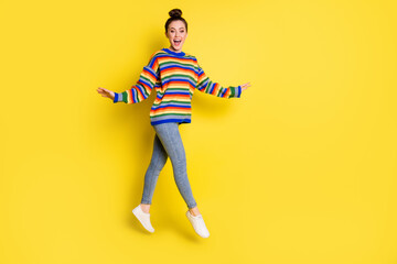 Fototapeta na wymiar Full body photo of cheerful charming lady wear rainbow color sweater jump up isolated on yellow color background