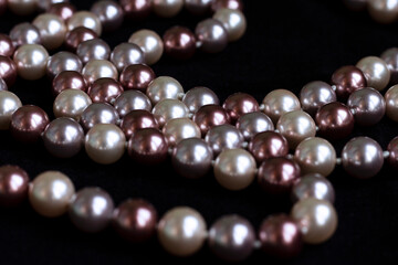 Necklace of pearls of different colors on black velvet.