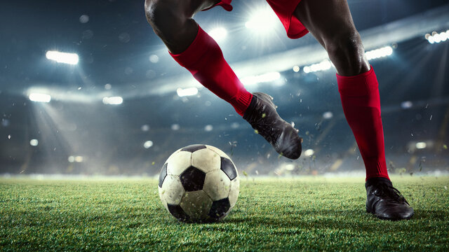 Cropped. Young male soccer or football player kicking ball during match at the stadium in flashlights, spotlights. Concept of professional sport, motion, movement. 3D render. Flyer for ad.