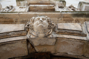 visage sculpté au dessus d'une porte en pierre