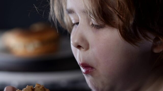 child is biting and chewing deep-fried chicken leg in fast food restaurant, closeup