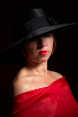 Portrait of ugle middle-aged woman with hat and red dress. Ugly model looking as lady posing in studio.