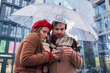 Couple standing under the rain and call a taxi