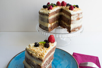 A delicious cake with whipped cream, blackberries and strawberries on top of the cocoa cake.