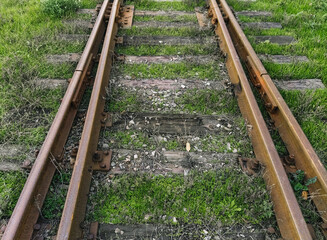 Old rusty metal rails and wooden sleepers on a dirt surface. Railroad for passenger and freight trains.