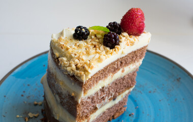 A delicious cake with whipped cream, blackberries and strawberries on top of the cocoa cake.