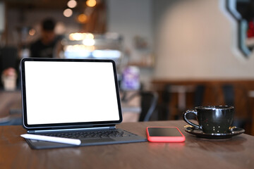Close up view of a tablet computer, stylus pen, smart phone and coffee cup on wooden desk with...