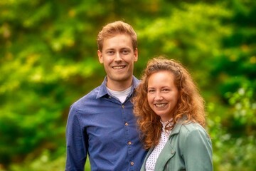 Portrait of a beautiful young couple in the forest. Green blurred background