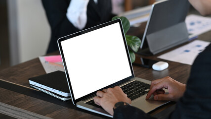 Close up view businessman hands typing on laptop computer and sitting with his colleague in office.