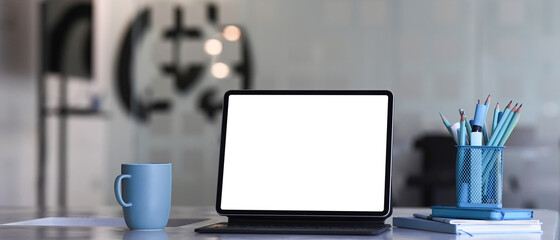 Designer workspace with tablet computer, coffee cup, stationery and notebook on white desk. Blank screen for graphics display montage.