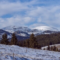 Fototapeta na wymiar Beautiful winter panoramic natural mountain landscape. Attractive snowy peaks of Rila Mountains, Bulgaria. White clouds in dynamic blue sky, perfect conditions for tourism recreation and winter sports