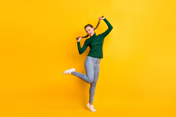 Fototapeta na wymiar Full length body size photo childish playful girl dancing laughing touching pigtails isolated on bright yellow color background